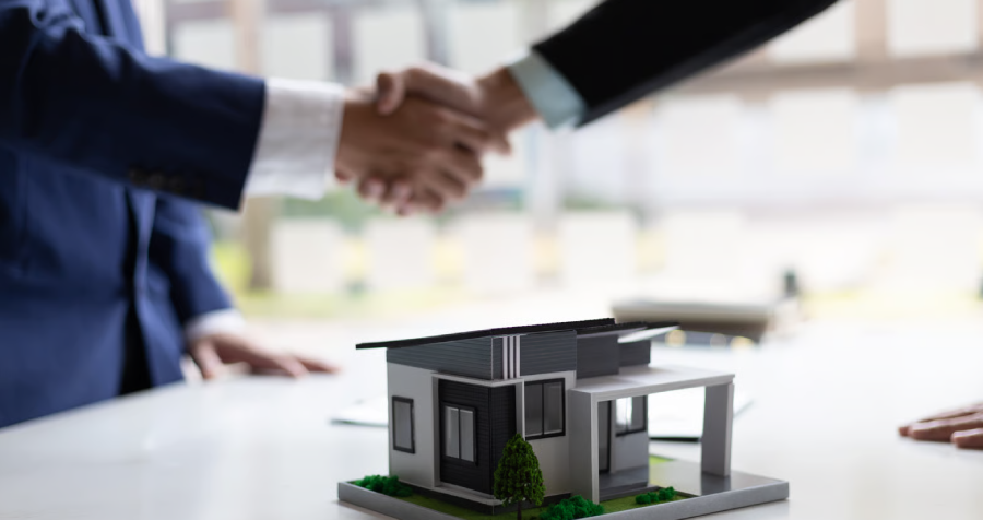Businessman and real estate agent shaking hands after negotiating home purchase agreement.
