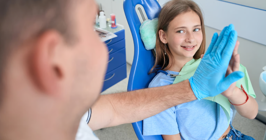 Joyous dental clinic patient high-fiving pediatric dentist